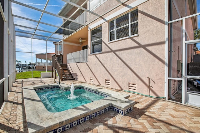 view of pool featuring glass enclosure, a jacuzzi, and a patio