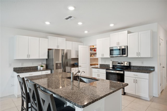 kitchen with appliances with stainless steel finishes, a center island with sink, white cabinetry, and sink