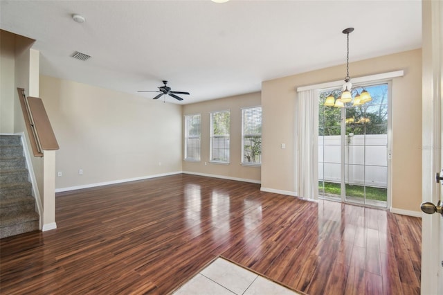 unfurnished living room featuring plenty of natural light, dark hardwood / wood-style flooring, and ceiling fan with notable chandelier