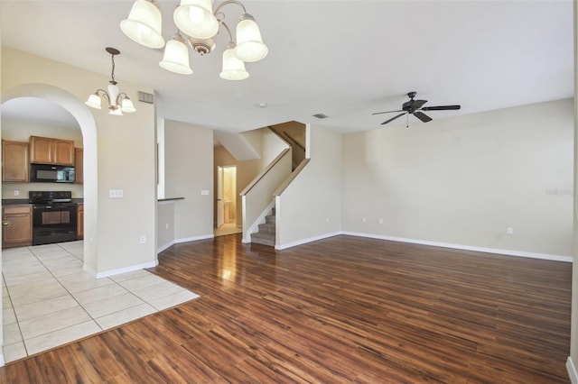 unfurnished living room featuring ceiling fan with notable chandelier and light hardwood / wood-style floors