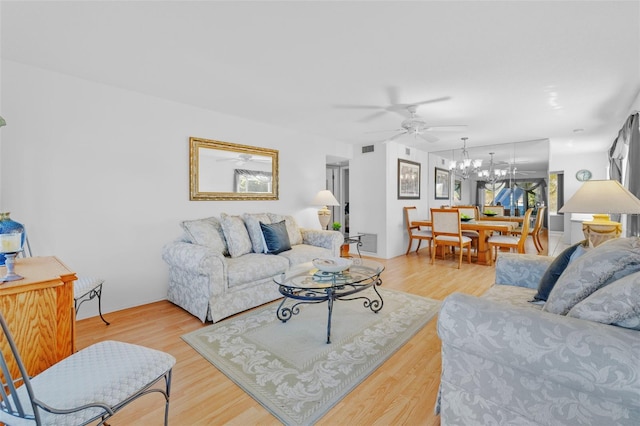 living room with ceiling fan with notable chandelier, wood finished floors, and visible vents