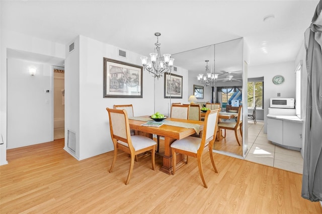 dining area featuring ceiling fan with notable chandelier, visible vents, and light wood-style floors