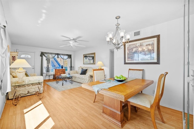 dining area with light wood-style floors, visible vents, and ceiling fan with notable chandelier