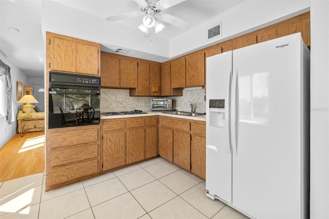 kitchen with visible vents, oven, stovetop, white fridge with ice dispenser, and a sink