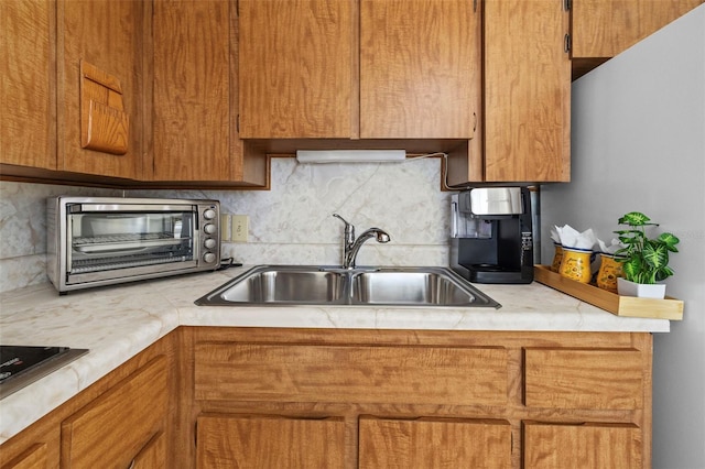 kitchen featuring a toaster, light countertops, a sink, and decorative backsplash