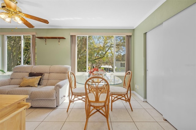 dining space featuring ornamental molding, light tile patterned flooring, ceiling fan, and baseboards