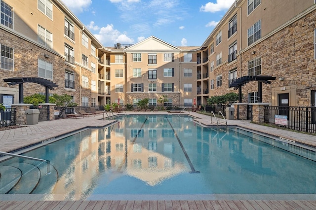 community pool featuring fence, a pergola, and a patio