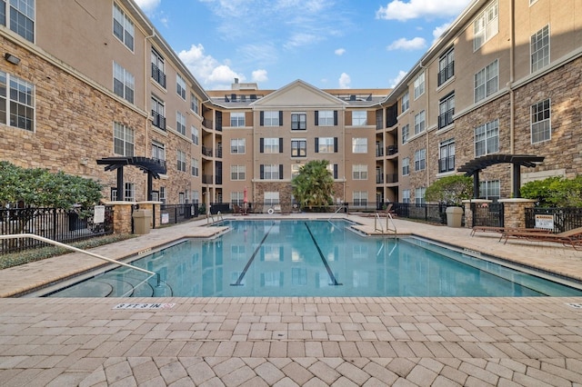 community pool featuring fence and a pergola