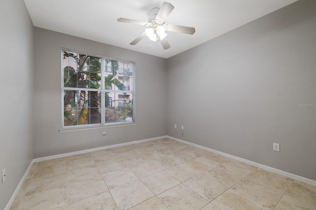 unfurnished room with a ceiling fan and baseboards