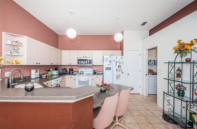 kitchen with kitchen peninsula, white appliances, decorative light fixtures, and sink