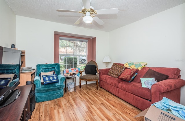 living room featuring ceiling fan, a textured ceiling, and light hardwood / wood-style flooring