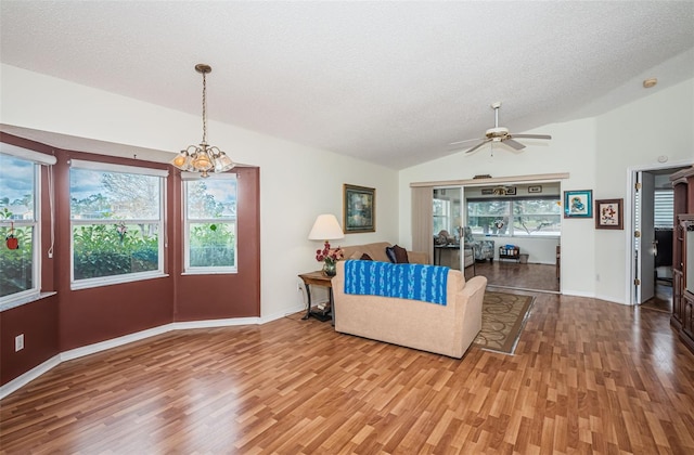 living room featuring ceiling fan with notable chandelier, hardwood / wood-style floors, a textured ceiling, and vaulted ceiling