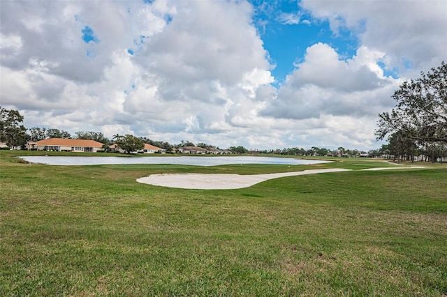 view of property's community with a water view and a lawn