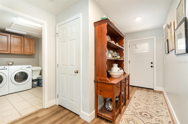 laundry area featuring washer and dryer, light hardwood / wood-style floors, and cabinets