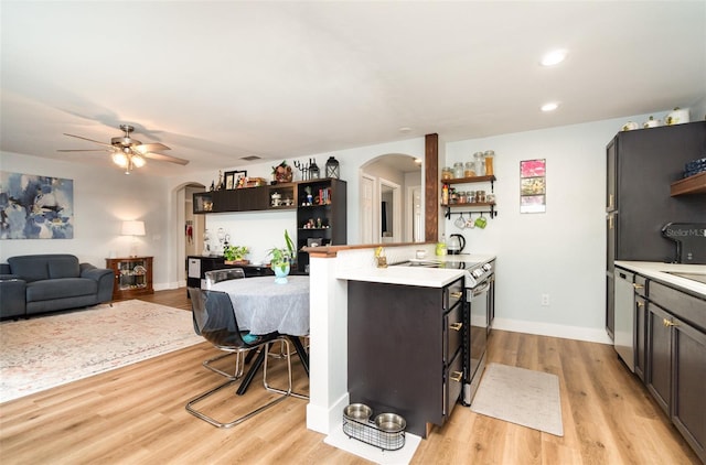 kitchen with kitchen peninsula, light wood-type flooring, dark brown cabinetry, stainless steel appliances, and ceiling fan