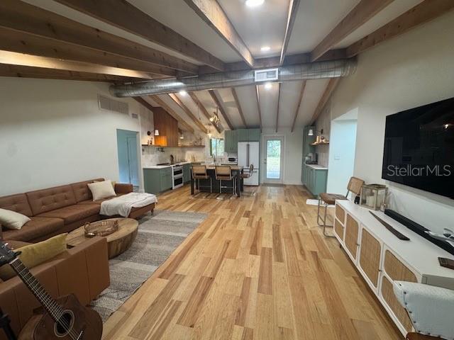 living room featuring lofted ceiling with beams and light wood-type flooring