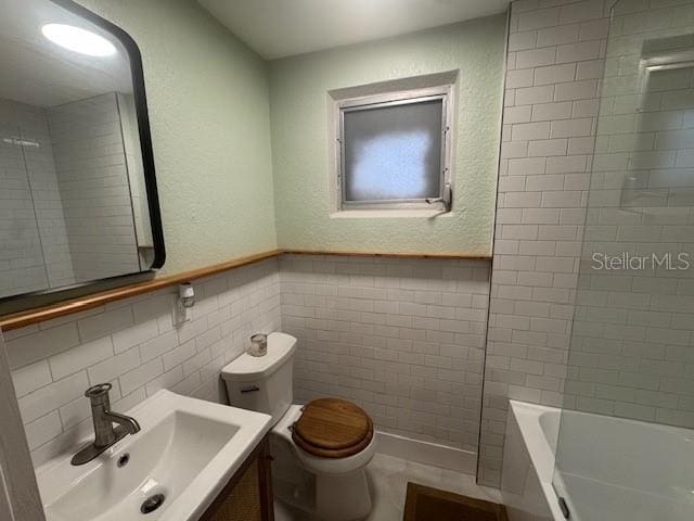 full bathroom featuring vanity, toilet, tile walls, and tiled shower / bath combo