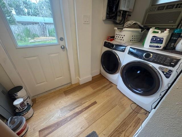 clothes washing area featuring washing machine and dryer, light hardwood / wood-style floors, and a wall mounted AC