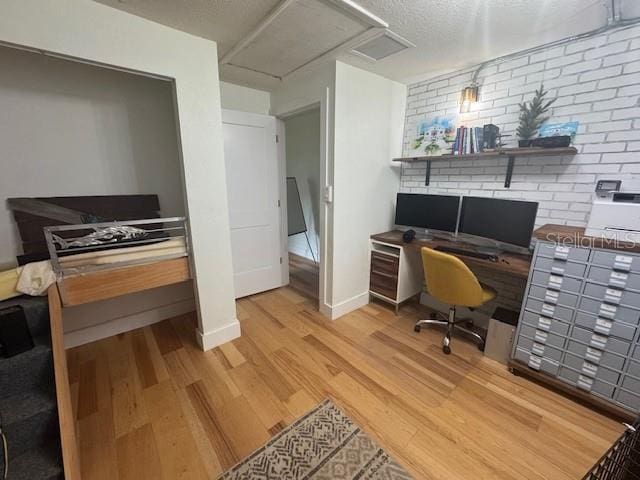 office area featuring hardwood / wood-style flooring, a textured ceiling, and brick wall