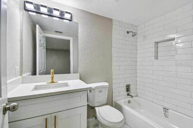 full bathroom with vanity, toilet, a textured ceiling, and tiled shower / bath combo