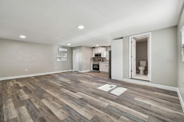 unfurnished living room featuring light hardwood / wood-style floors and a wall mounted AC