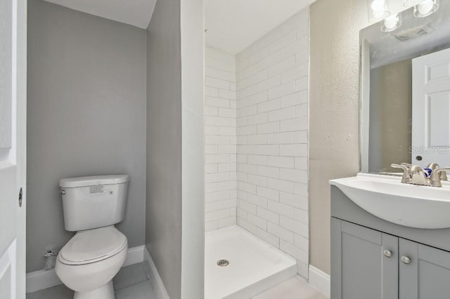 bathroom with vanity, toilet, and a tile shower