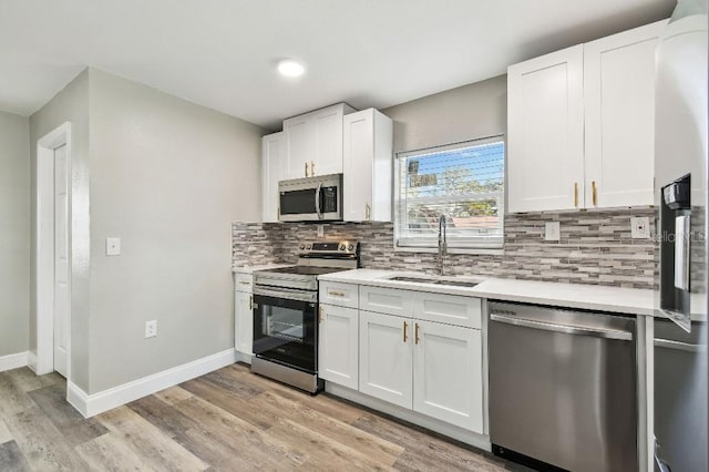 kitchen with decorative backsplash, appliances with stainless steel finishes, light wood-type flooring, sink, and white cabinetry