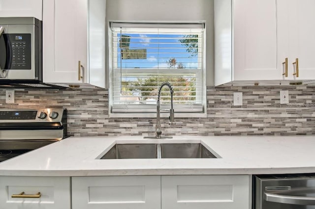 kitchen featuring backsplash, white cabinets, sink, light stone counters, and stainless steel appliances