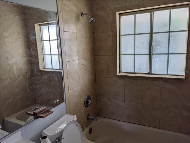 bathroom with toilet and tiled shower / bath