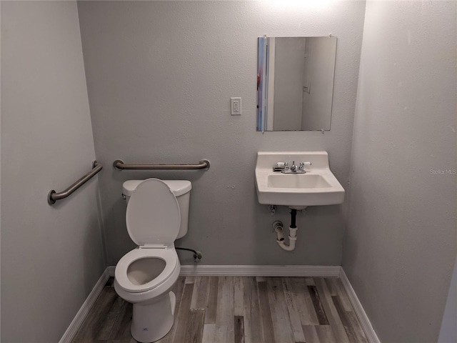 bathroom featuring toilet, wood-type flooring, and sink