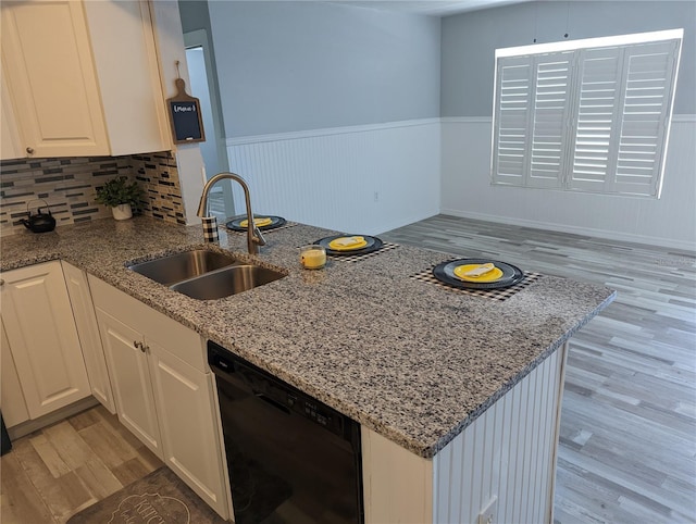 kitchen with white cabinets, sink, light stone countertops, light wood-type flooring, and black dishwasher