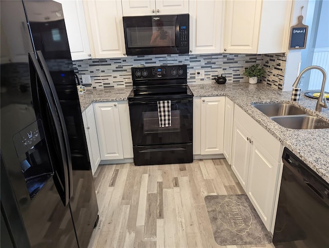 kitchen featuring black appliances, light stone counters, white cabinets, and sink