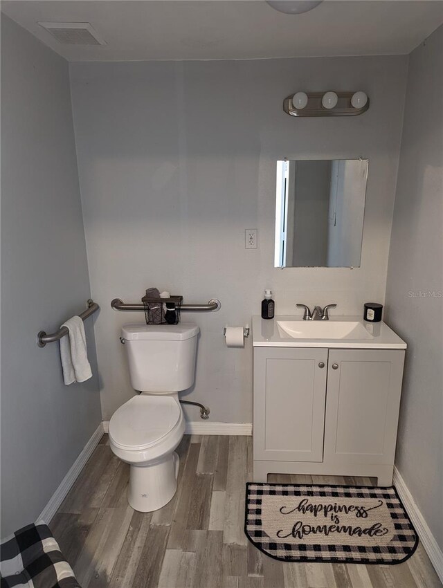 bathroom with hardwood / wood-style flooring, vanity, and toilet