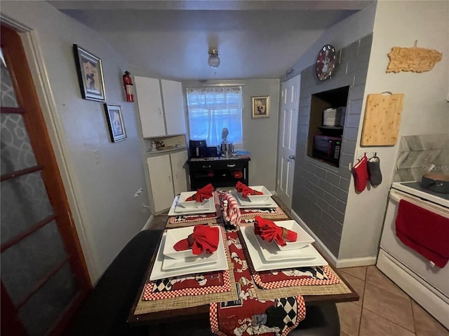 kitchen with electric range, white cabinetry, and light tile patterned floors