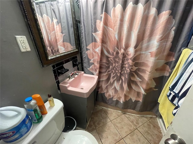 bathroom featuring tasteful backsplash, a shower with curtain, sink, tile patterned flooring, and toilet