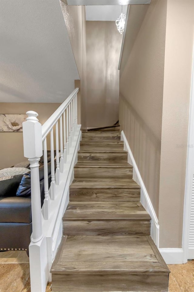 stairway featuring a notable chandelier