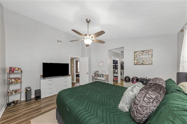 bedroom with a textured ceiling, ceiling fan, hardwood / wood-style floors, and lofted ceiling