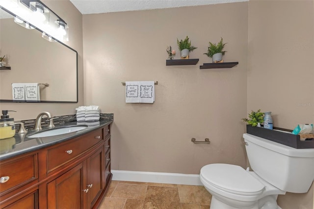 bathroom with toilet, baseboards, and vanity