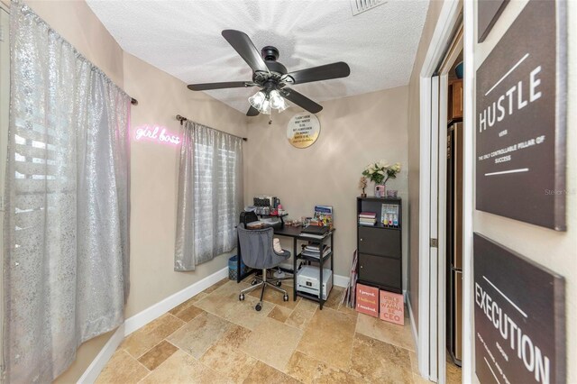 office space with stone tile floors, a textured ceiling, baseboards, and ceiling fan