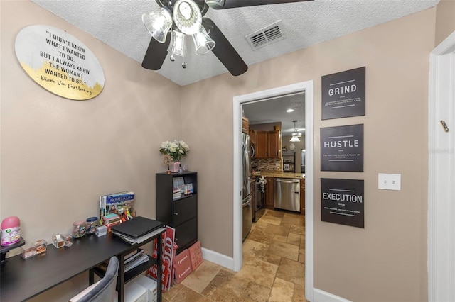 office space featuring stone finish flooring, visible vents, a textured ceiling, and baseboards