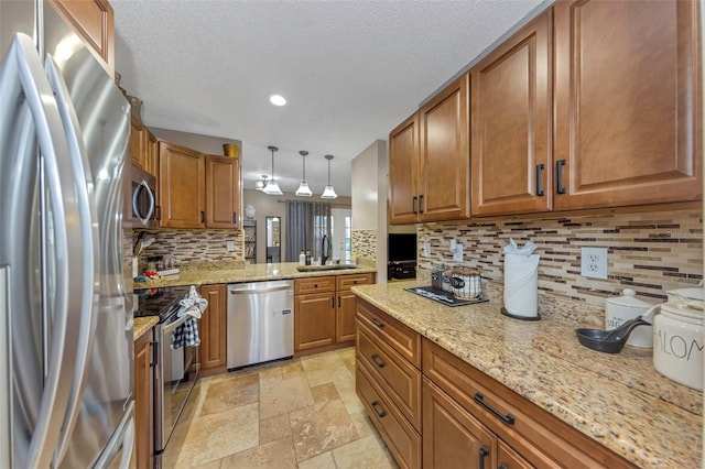 kitchen with stainless steel appliances, a sink, tasteful backsplash, brown cabinetry, and stone tile flooring