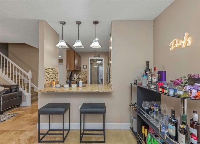 kitchen with a breakfast bar, brown cabinets, tasteful backsplash, a peninsula, and baseboards