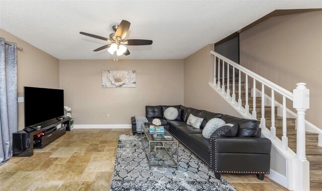 living area featuring a textured ceiling, a ceiling fan, baseboards, stairs, and stone finish flooring