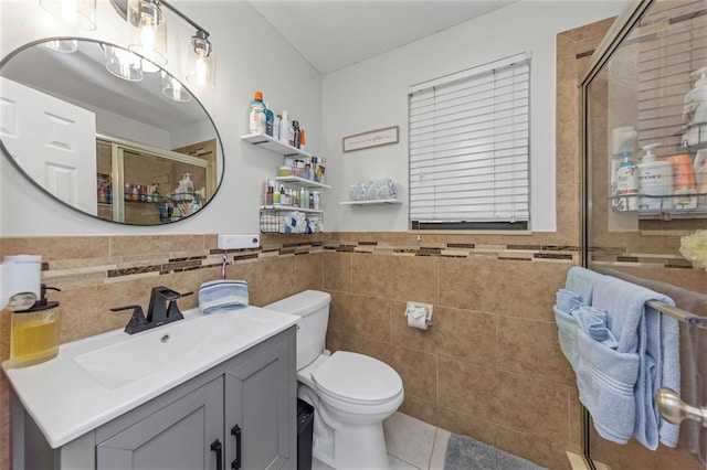 bathroom featuring tile walls, toilet, a stall shower, vanity, and tile patterned flooring