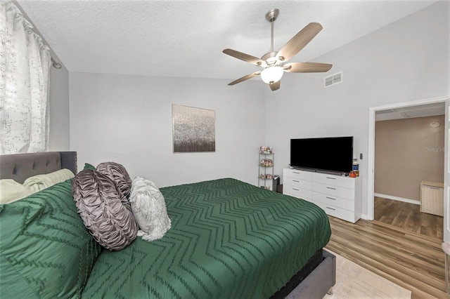 bedroom featuring a textured ceiling, wood finished floors, visible vents, a ceiling fan, and vaulted ceiling