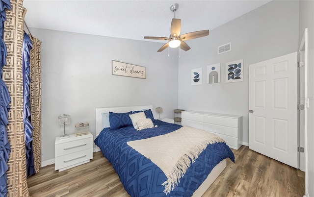 bedroom featuring lofted ceiling, ceiling fan, visible vents, and wood finished floors