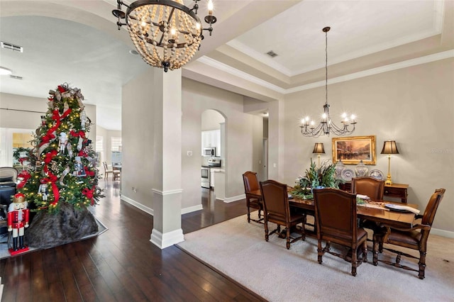 dining space with ornamental molding, hardwood / wood-style flooring, a raised ceiling, and a notable chandelier