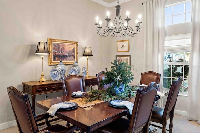 dining room with light carpet, ornamental molding, and a notable chandelier