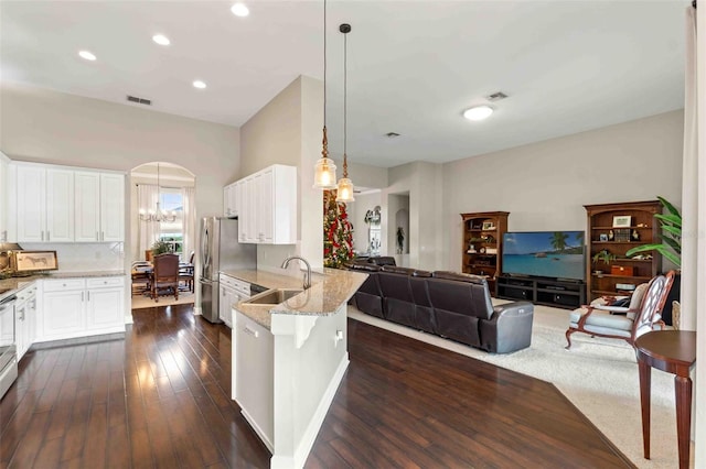 kitchen featuring pendant lighting, kitchen peninsula, sink, light stone countertops, and white cabinetry