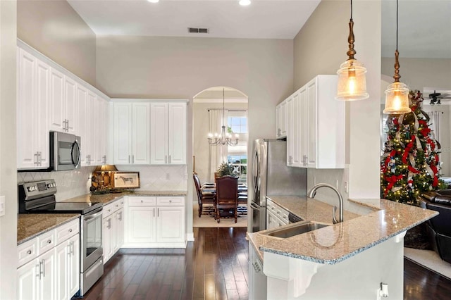 kitchen with pendant lighting, sink, a kitchen bar, white cabinetry, and stainless steel appliances